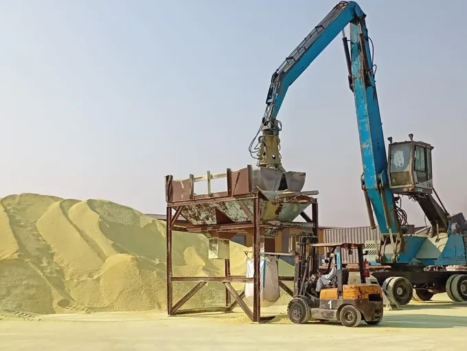 Material handler and forklift at work beside bulk cargo