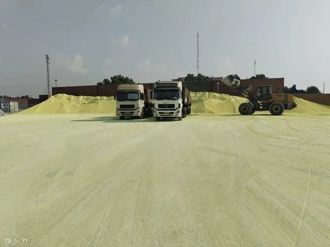 Trucks and a loader positioned beside bulk stockpiles